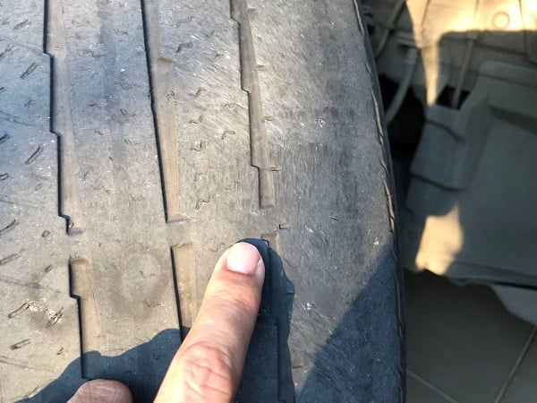 Bald tire with finger showing tread