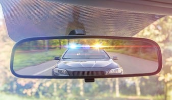 Police car with lights on in rear view mirror