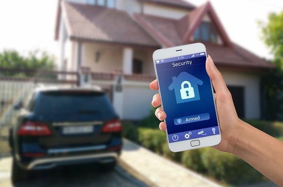 Hand holding Smart phone with security app outside home