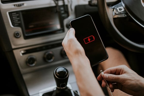 Hand with cell phone with low battery plugging into phone charger