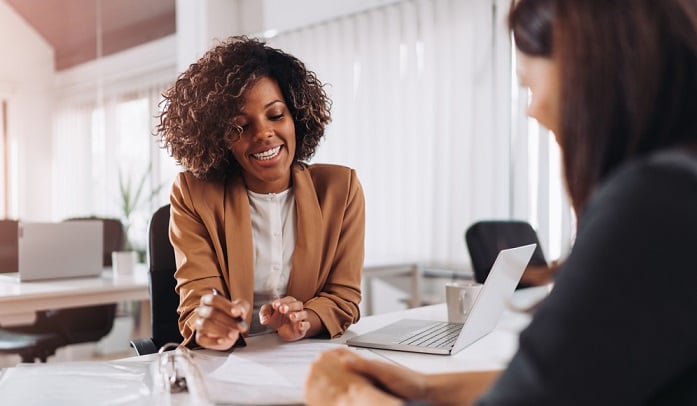 Happy woman discussing insurance documents with woman customer