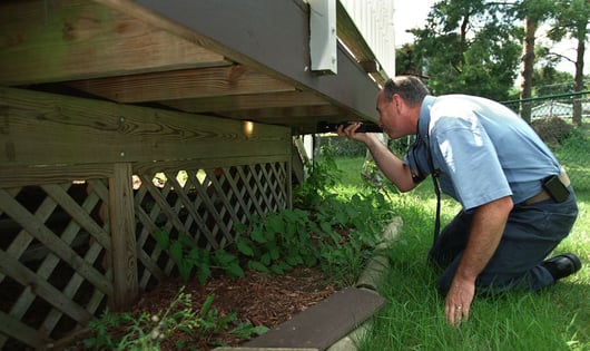 professional deck inspector looking ubnder a home deck