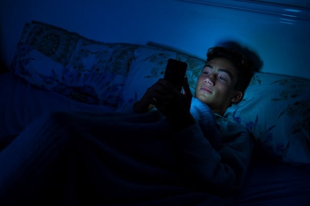 teen in bed on cell phone