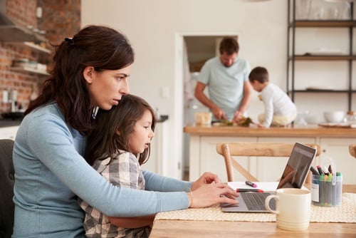 Young family at work in kitchen with mom and daughter on computer and father and son working at kitchen counter